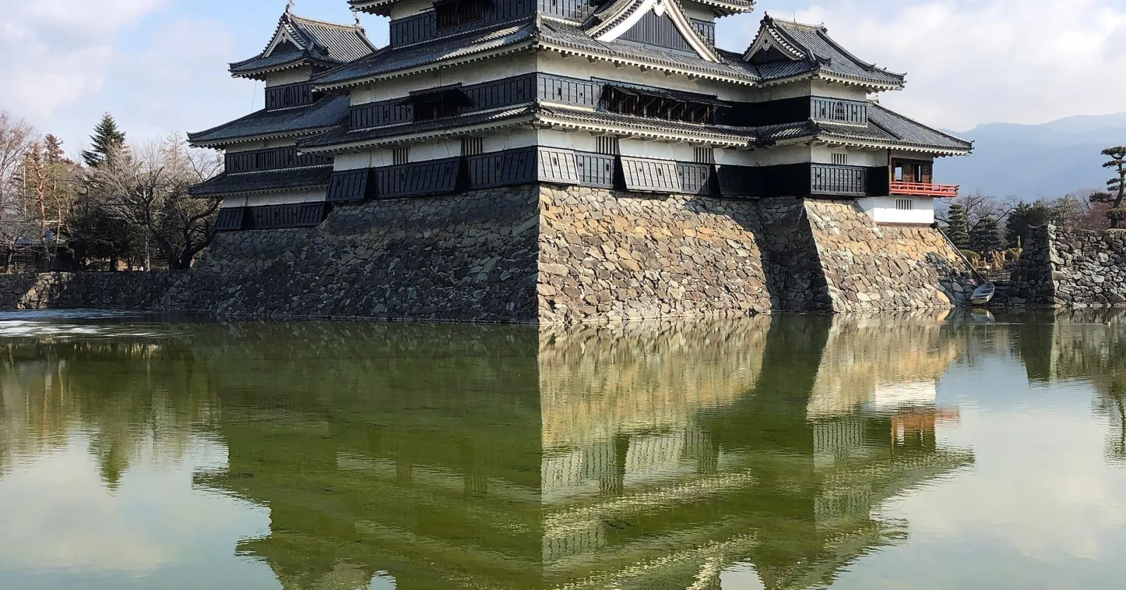 Matsumoto Castle and its red bridge reflected in the moat